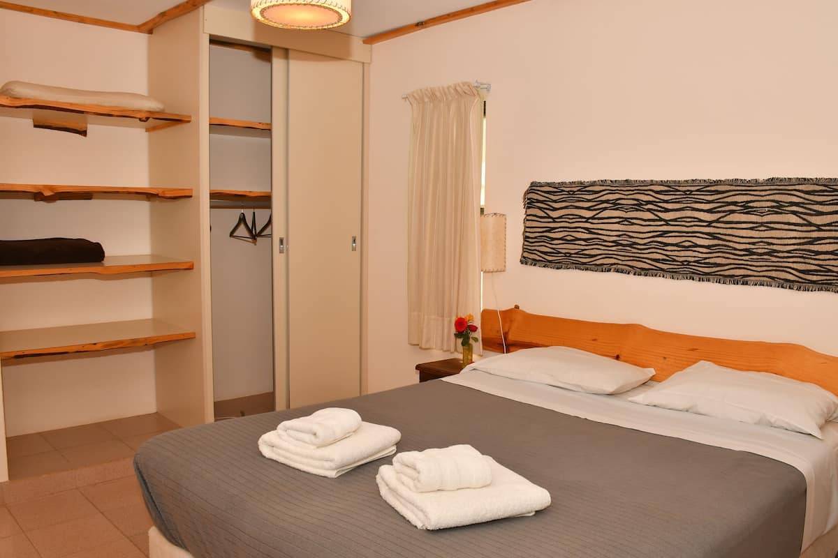 Una habitación de hotel con una cama, un armario, una mesita de noche y una obra de arte colgada en la pared.