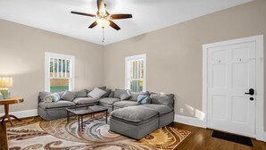A living room with a sectional sofa, a ceiling fan, and a patterned rug. - Charming 3BR/2BA Sleeps 6 in Graham, NC has everything you need! (Graham)