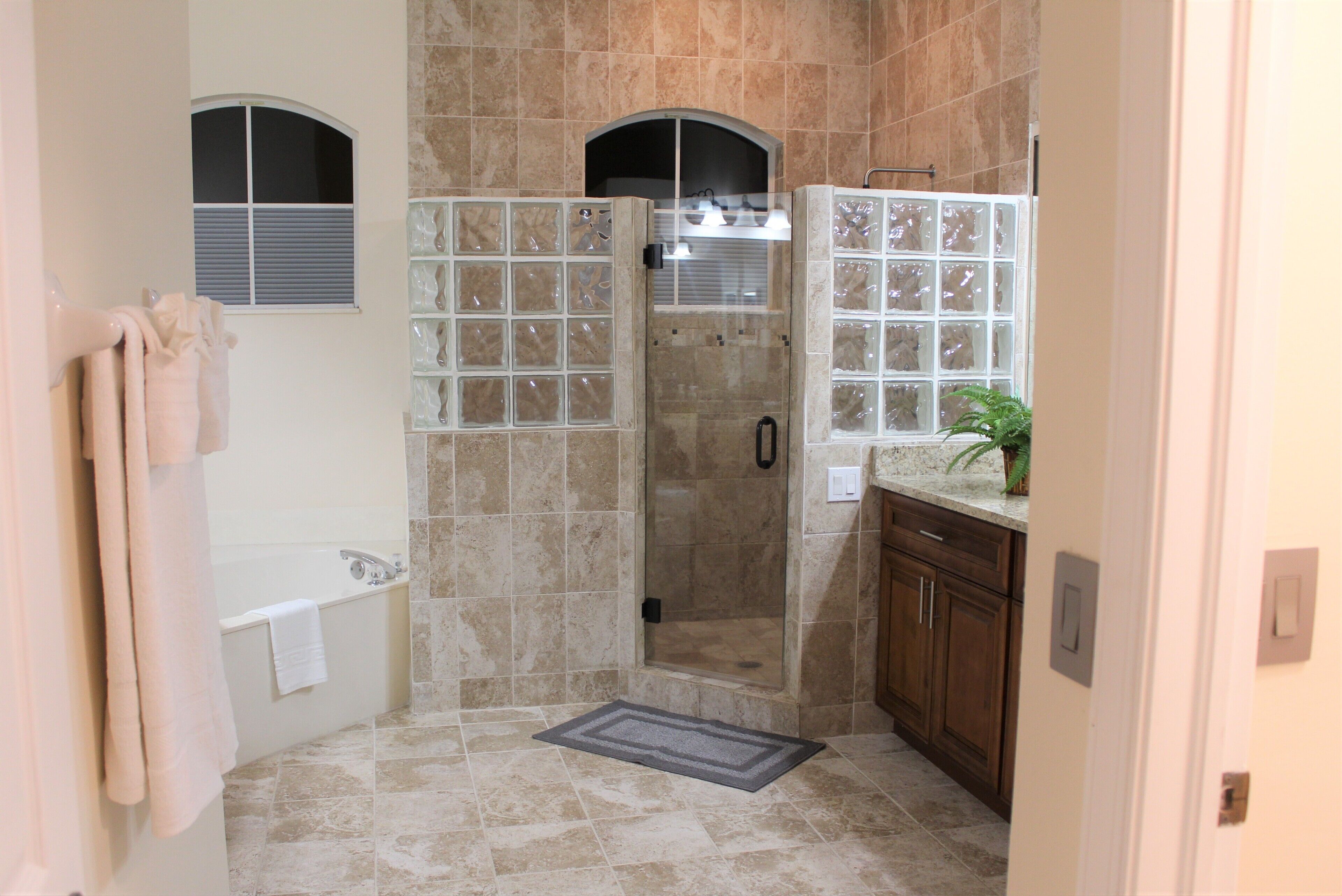 Une salle de bain dotée d’une douche à parois de verre, d’une baignoire et d’un meuble-lavabo avec un évier.