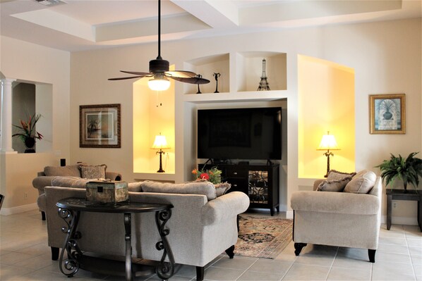 A living room with two sofas, a coffee table, a TV, and decorative lamps.