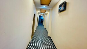 A hotel hallway with a checkered floor, a ceiling with recessed lighting, and a framed picture on the wall. - Hotel Jay Shree (Ujjain)