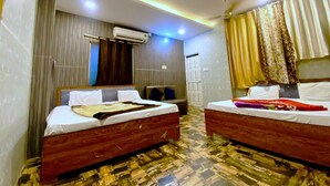 A hotel room with two beds, a ceiling fan, an air conditioning unit, and patterned flooring. - Hotel Jay Shree (Ujjain)