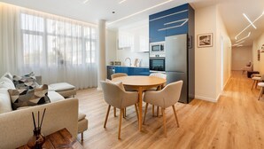 Una sala moderna con comedor, cocina y un pasillo que lleva a un dormitorio.