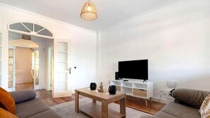A modern living room with a wooden coffee table, a flat-screen TV on a white stand, and a sofa.