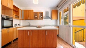 A modern kitchen with wooden cabinets, a central island, and a large window with a yellow view.