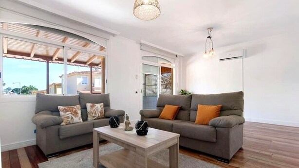 A modern living room with two sofas, a coffee table, and a hanging light fixture.