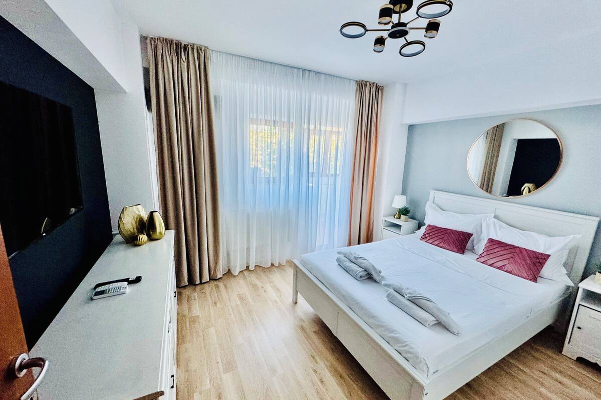 A hotel room with a bed, a desk, a TV, and a window with curtains.