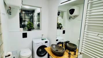 Un baño pequeño con inodoro, lavadora y lavabo.