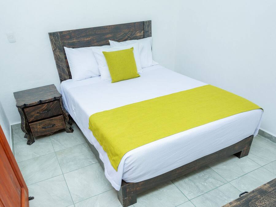 A bed with a wooden headboard, white bedding, and a yellow throw blanket.