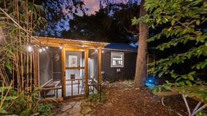 Una struttura in legno con una porta in vetro, una piccola finestra e un sentiero in pietra che vi conduce.