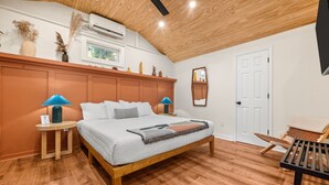 Una camera da letto con un letto in legno, due lampade ai comodini, un comodino, una sedia e una porta.
