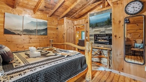 Ein Holzhütten-Interieur mit einem Bett, einem Kamin und einer Wanduhr.