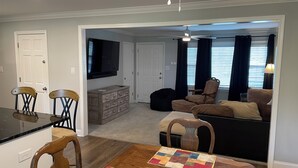 Ein Wohnzimmer mit einer Couch, einem Couchtisch und einem an der Wand befestigten Fernseher.