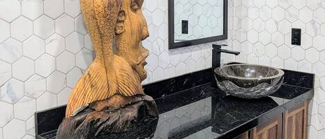 Et badeværelse med en trækommode, en marmorvask og en backsplash med hexagonfliser.