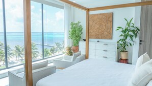 A bedroom with a large bed, a view of the ocean, and several potted plants. - Clearwater Belize (San Pedro)