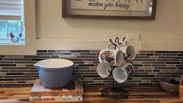 Una cocina con encimera de madera, un cartel enmarcado que dice 'DO WHAT makes you happy', y una ventana con persianas.