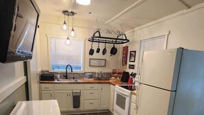 A compact kitchen with white appliances, a wooden floor, and a ceiling fan. - Cozy Cabin on 22 Private Acres in Smithville, TX Peaceful Hill Country Retreat (Smithville)
