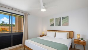 A bedroom with a bed, a nightstand, a ceiling fan, and artwork on the wall.