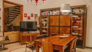 Ein Essbereich mit Holztisch und -stühlen, einem Fernseher auf einem Schrank sowie einer Treppe zu einer anderen Ebene.
