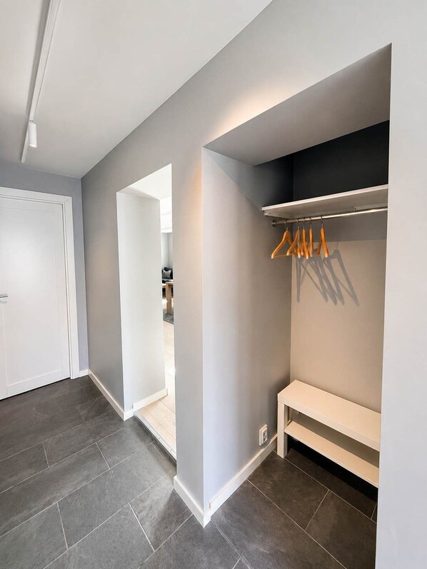 A hallway with a coat rack, a bench, and a door leading to another room.