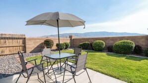 Un patio con mesa y sillas, una sombrilla y vistas a las montañas.