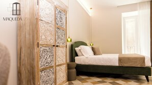 A bedroom with a green bed, a wooden wardrobe with intricate designs, a small round stool, and a checkered floor. - Maqueda 259 - In Palermo's Lively Heart (Palermo)