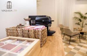 A wicker basket with a framed picture on a wooden table, a black grill, and a chair in a modern room with a checkered floor. - Maqueda 259 - In Palermo's Lively Heart (Palermo)