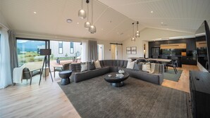 Amplia sala de estar con un sofá seccional grande, una mesa de comedor y una cocina al fondo.