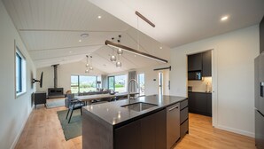 Cocina moderna con una isla grande, armarios oscuros y vistas al exterior.
