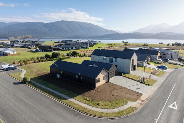 Un quartier résidentiel avec des maisons modernes, une route et un lac en arrière-plan.
