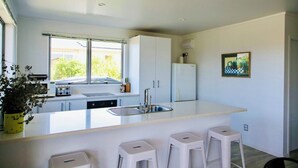 A modern kitchen with a large island, white cabinetry, and a window with a view of greenery.