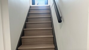 A staircase with wooden steps and a black handrail. - Spacious 5-bedroom house in welcoming West Des Moines with AC (West Des Moines)