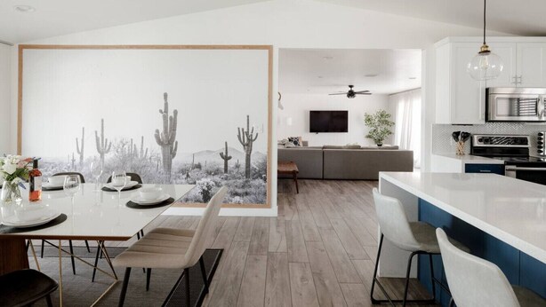 A modern kitchen with white cabinets, a built-in oven, and a dining area with a cactus-themed wall art. - Chic Scottsdale Stay | Pool, Hot Tub! (Scottsdale)