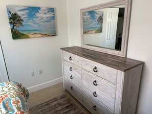 A bedroom with a bed, a dresser, a mirror, and a beach-themed painting on the wall. - Lovely ❤ Cottage near the Beach & Downtown SRQ. (Sarasota)