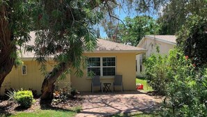 Une maison avec une allée pavée menant à un petit patio équipé de deux chaises et d’une table.