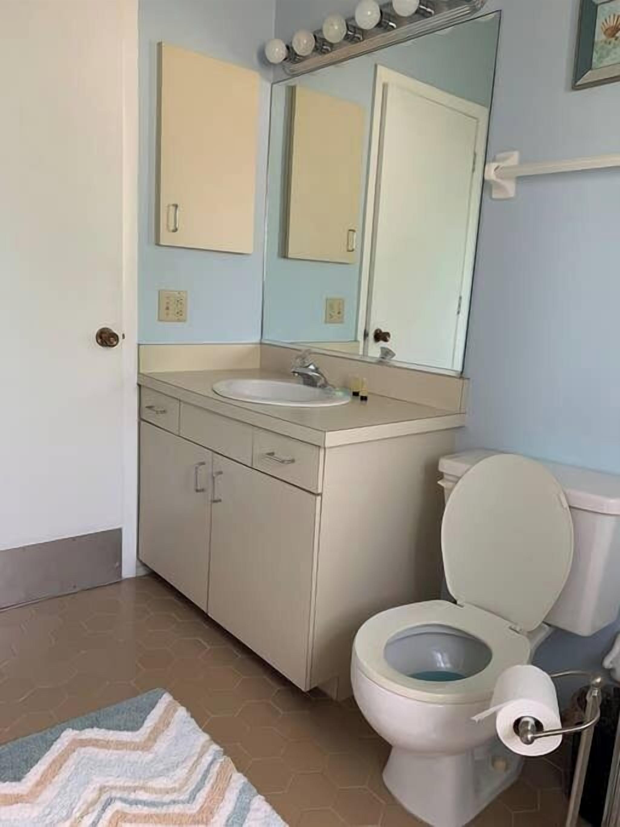 Un bagno con WC, lavandino e specchio.