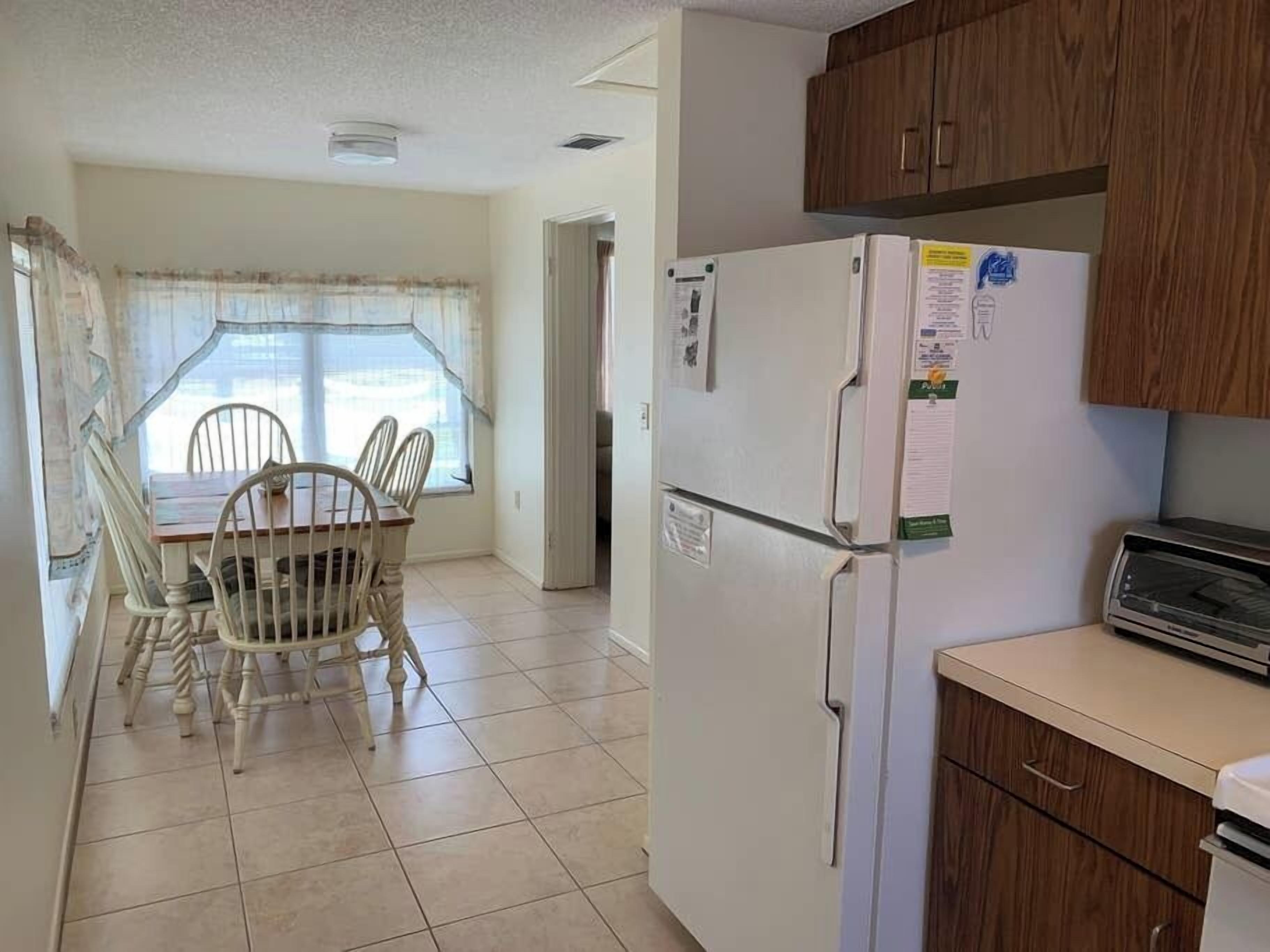 A compact kitchen with a refrigerator, a toaster, and wooden cabinets.