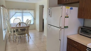 Cocina compacta con refrigerador, tostadora y armarios de madera.