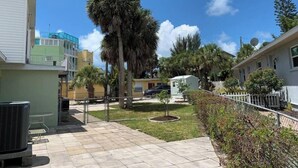 Zona residencial con patio empedrado, palmeras y un pequeño jardín.
