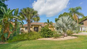 A house with a well-maintained lawn, palm trees, and a clear sky.
