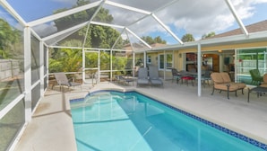 A covered outdoor swimming pool with lounge chairs and a patio area.