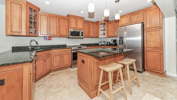 A modern kitchen with wooden cabinets, stainless steel appliances, and a granite countertop.