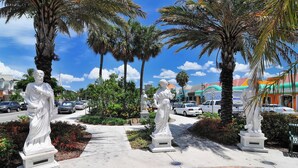 Un sentier bordé de statues, avec des palmiers et un ciel dégagé.