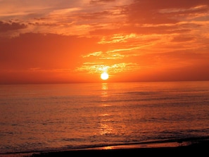 A sunset over a calm sea with a clear horizon.