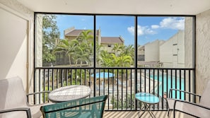 A balcony with a pool, chairs, and a table.