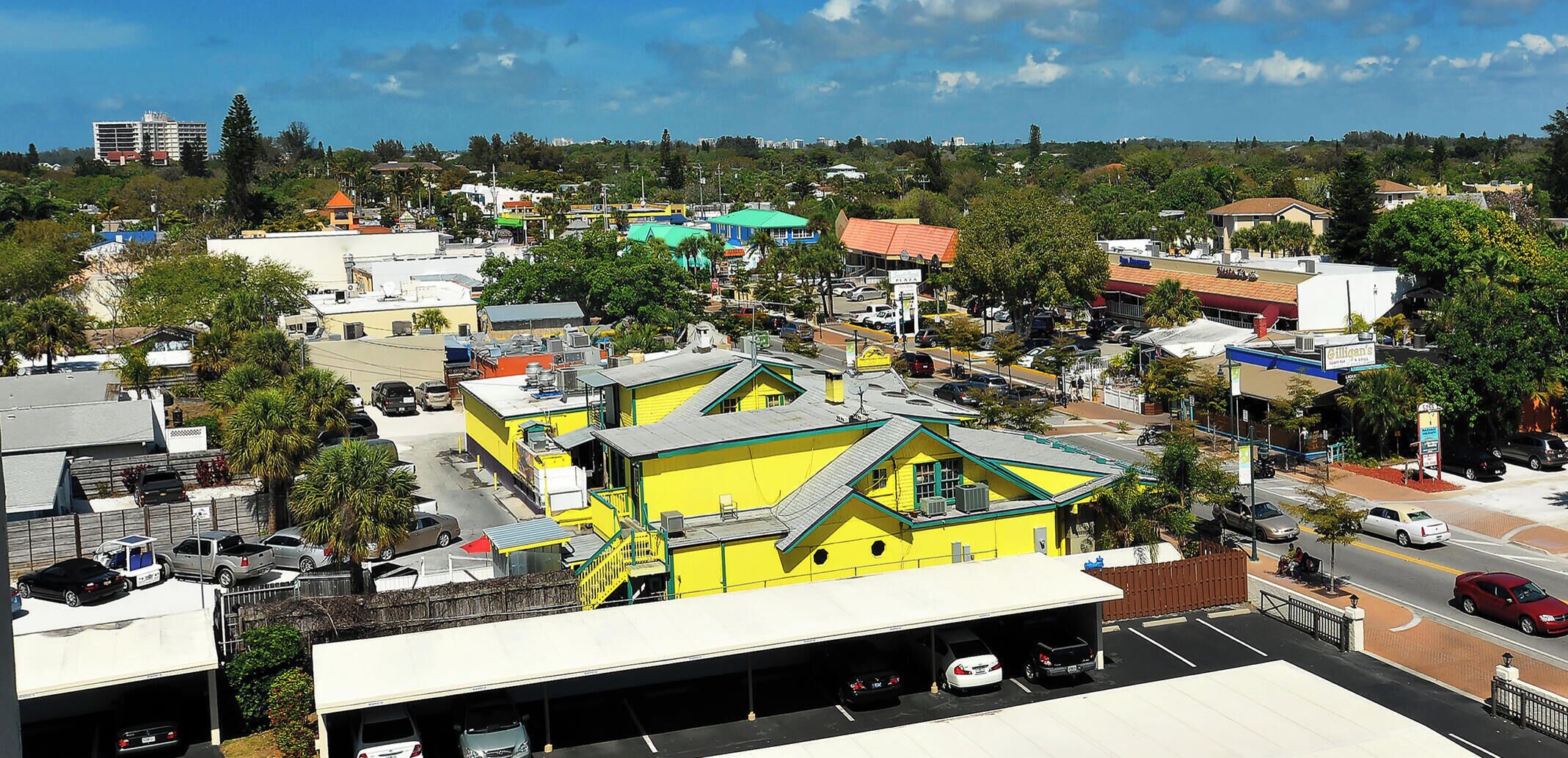 A yellow building with a flat roof and a parking lot in front.