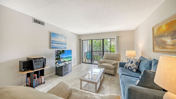 A living room with a sofa, a coffee table, a TV, and a bookshelf.