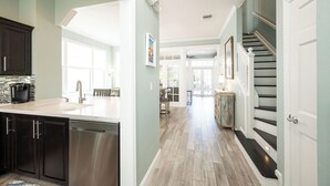 Una cocina moderna con lavavajillas, un comedor con mesa y sillas, y una escalera que lleva a un segundo piso.