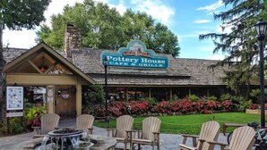 En rustik utomhusplats med sittplatser, Adirondack-stolar och en eldstad av sten vid Old Mill Pottery House Cafe & Grille.