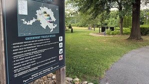 En informationsskylt för Riverwalk Greenway med information om regler för vandringslederna, en karta och kontaktuppgifter.